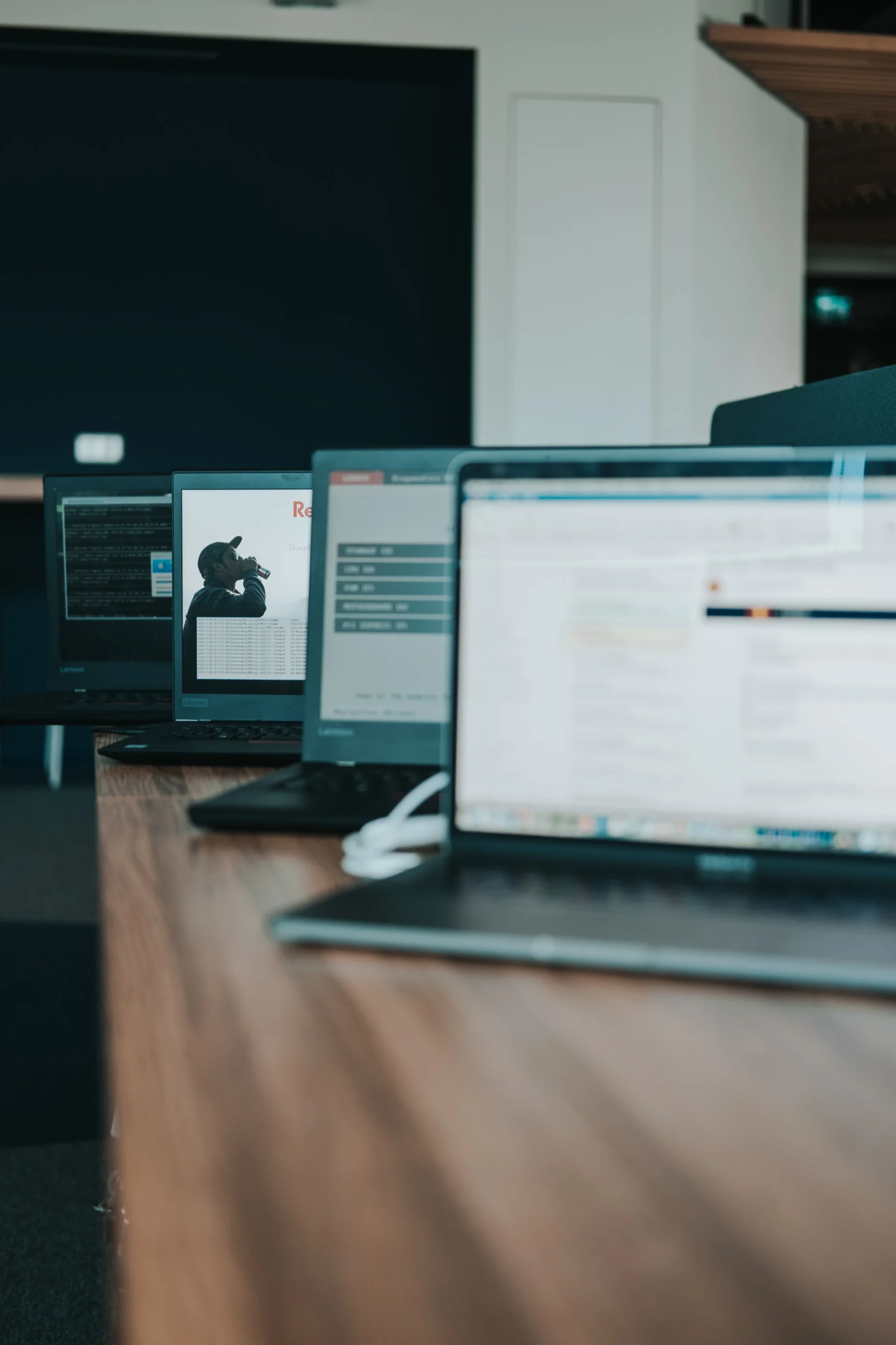 Plusieurs ordinateurs portables affichant du code et des interfaces pour évaluer les compétences techniques d'une agence web.