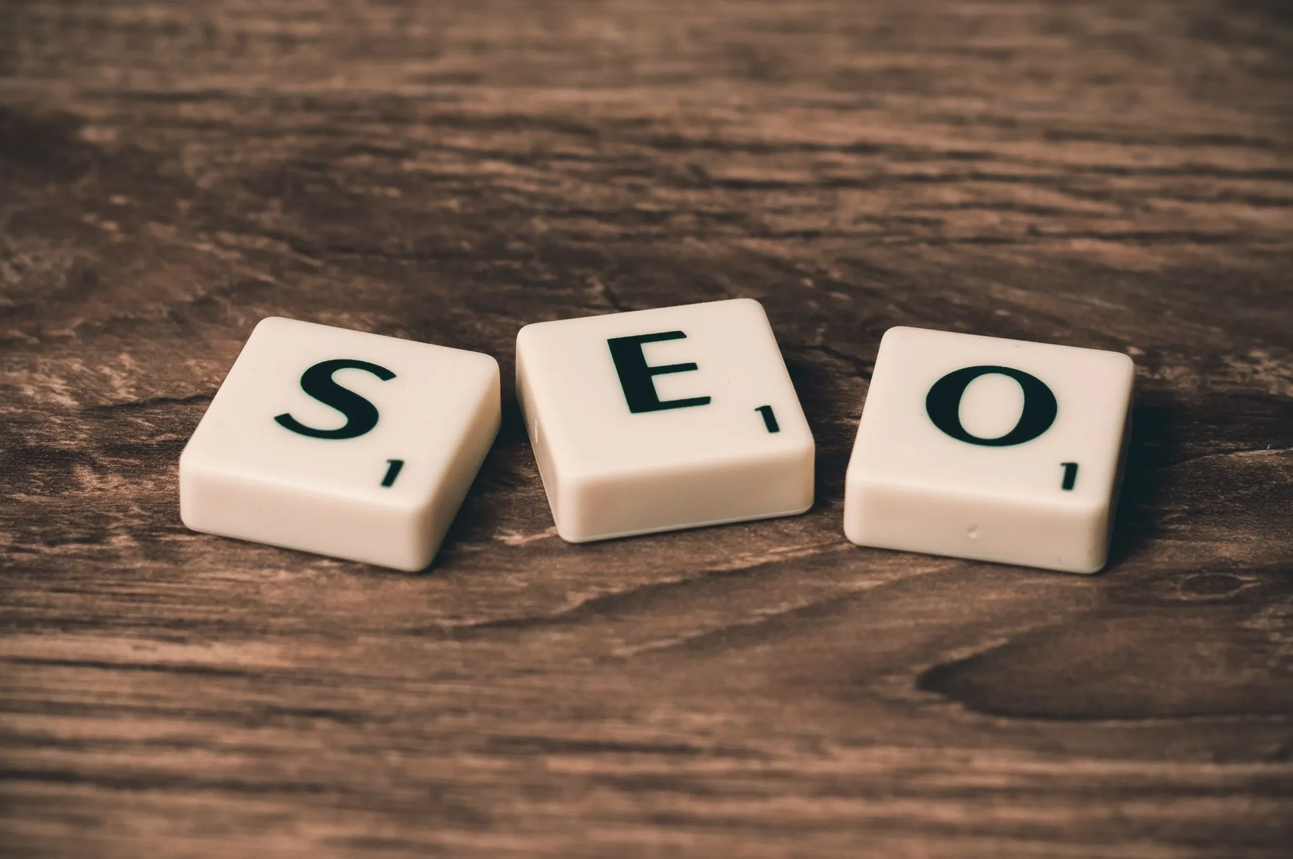 Lettres en bois formant l'acronyme SEO pour illustrer les bases du référencement naturel d'un site web.