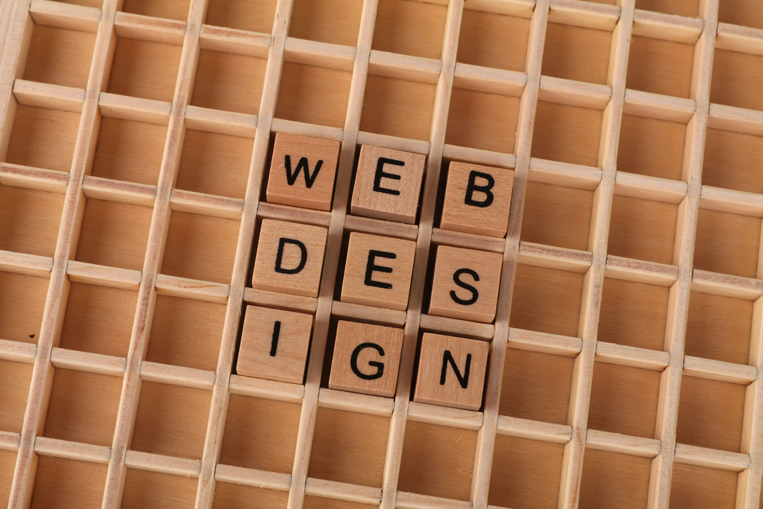 Lettres en bois formant l'expression Web Design intégrées dans une structure en bois pour illustrer la conception de sites web.