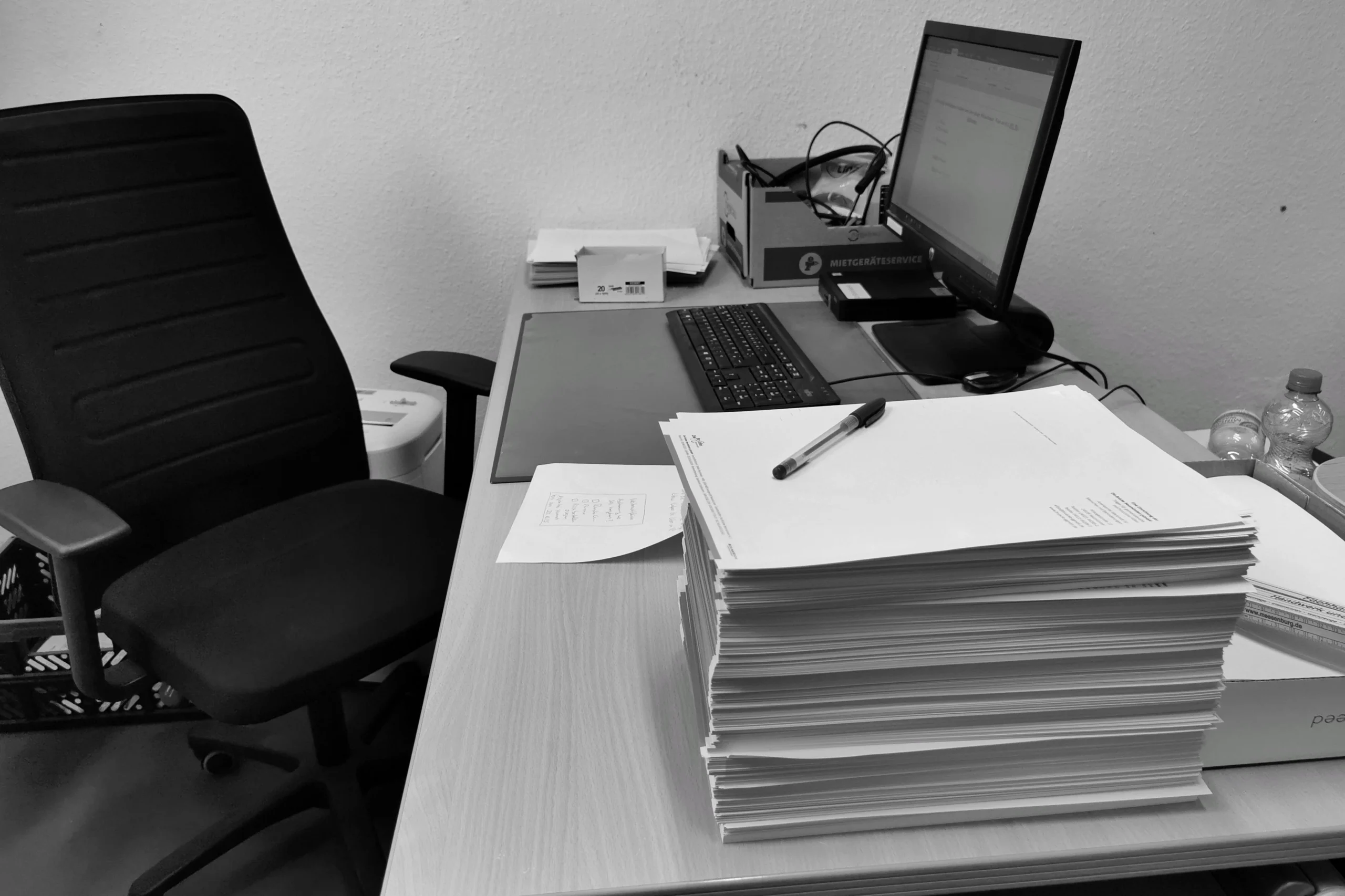 Poste de travail avec des piles de feuilles volantes et des classeurs de rangement.