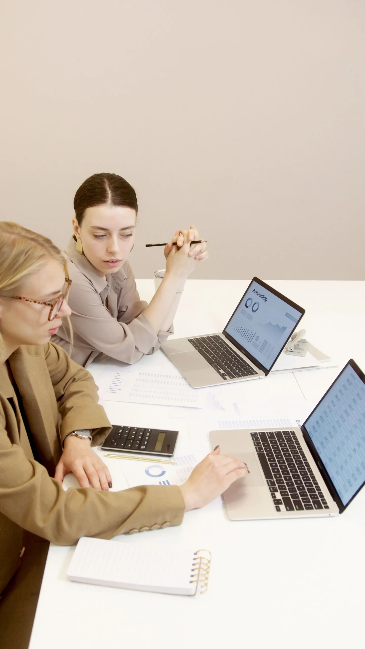 Deux collaboratrices travaillant sur des ordinateurs portables affichant des données comptables et des graphiques financiers