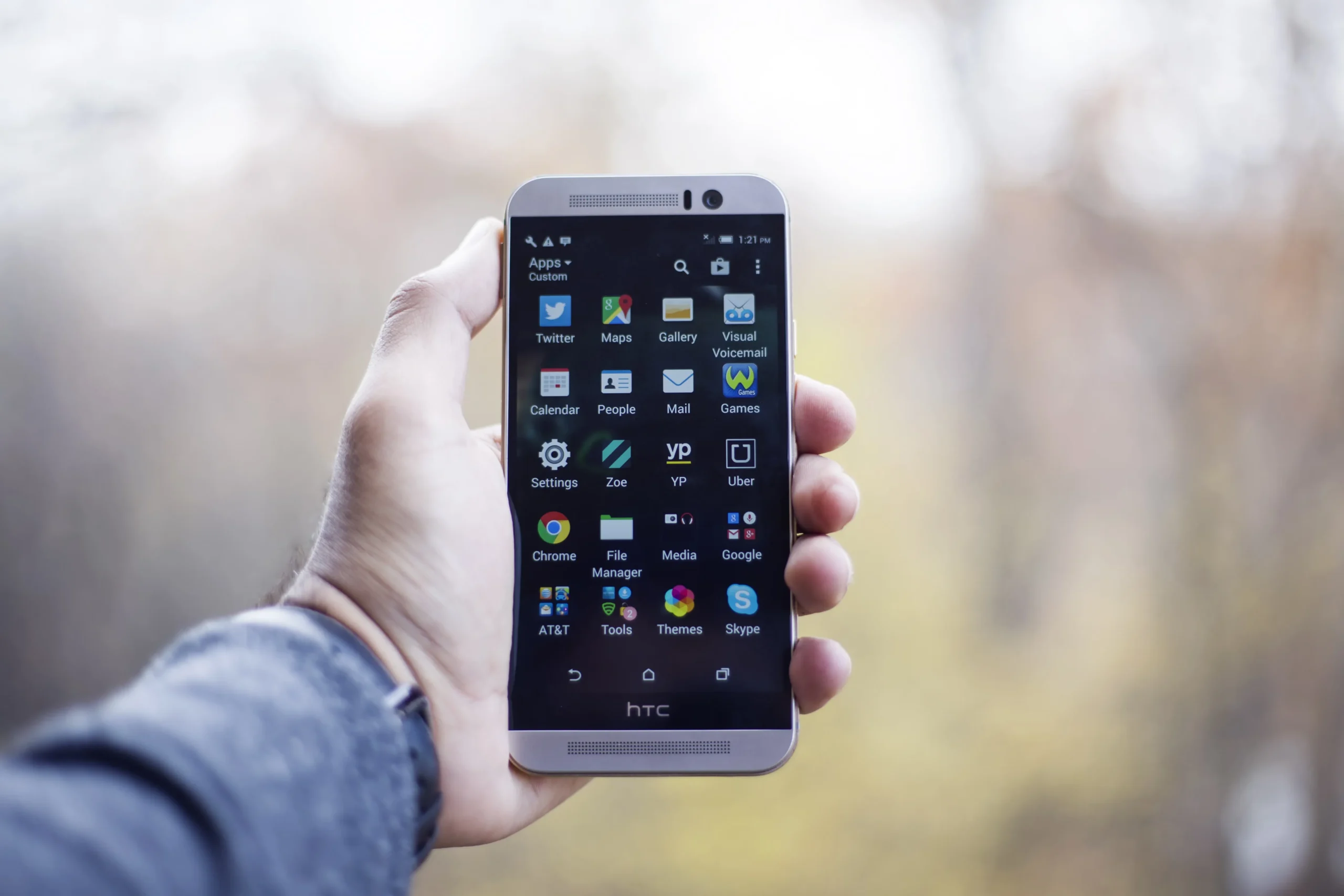 Main tenant un smartphone affichant une grille d'applications mobiles.
