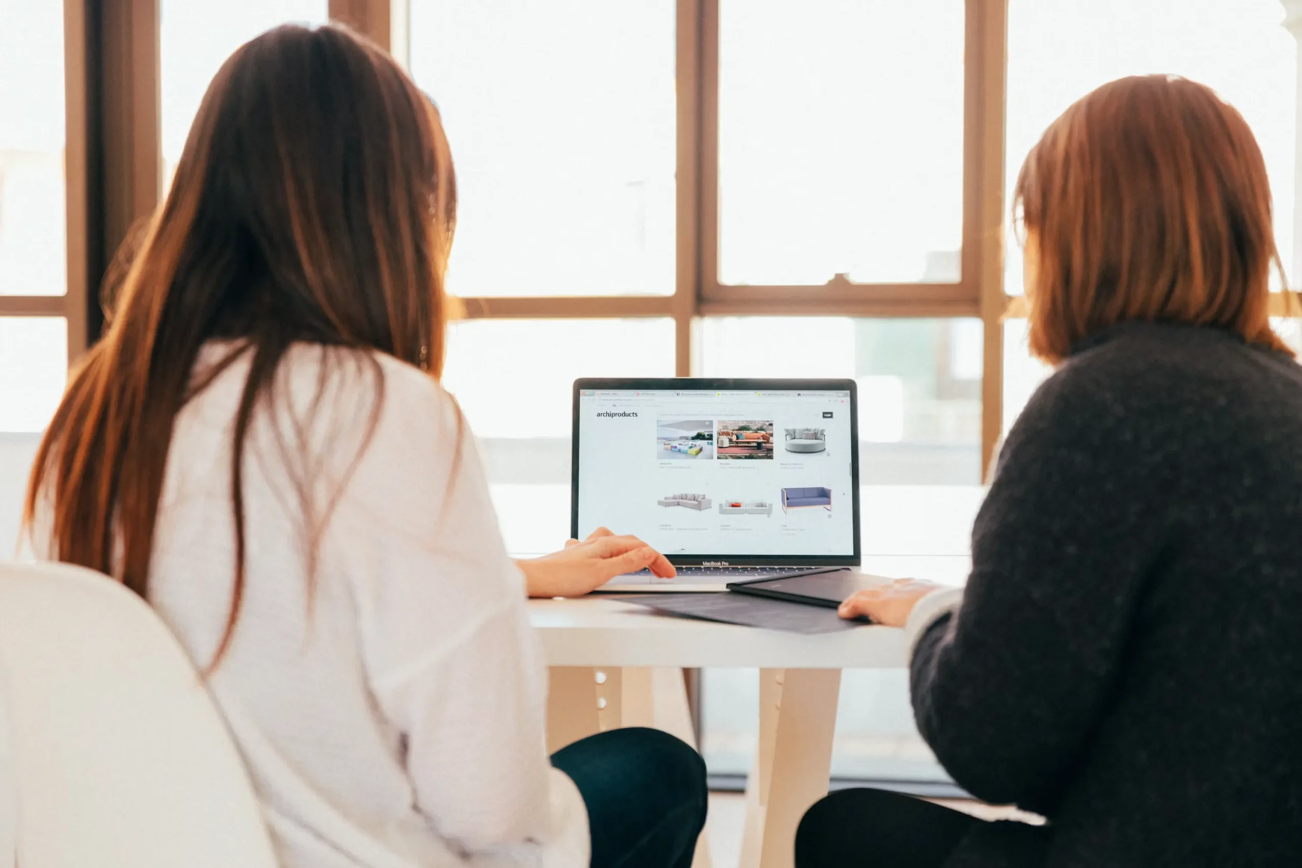 Deux collègues de travail discutant devant un ordinateur portable dans un bureau.